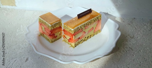 Fotografie A delectable slice of cake with rich layers of cream and frosting, topped with fresh fruit or sprinkles