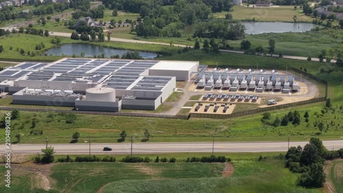 Aerial view of a data center with solar panels on the roof, AI center structure surrounded by roads and green countryside areas