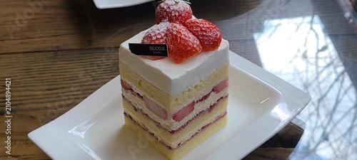 Obraz na płótnie A delectable slice of cake with rich layers of cream and frosting, topped with fresh fruit or sprinkles