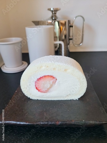 Soft roll cake with fluffy sponge layers and creamy filling spiraled inside, showcasing smooth texture, delicate shape, and sweet inviting appearance in close-up detail