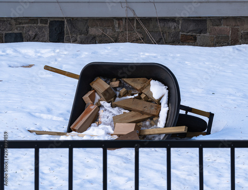 Wheelbarrow with firewood in snowy yard