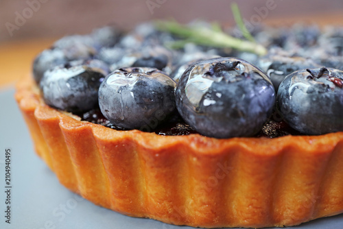 Macro front view of a crispy golden crust blueberry tart packed with fresh ripe berries