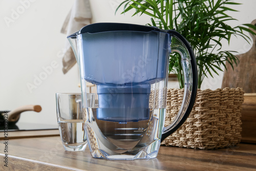 Canvas Print Water filter pitcher with a glass of purified water on a wooden kitchen counter,