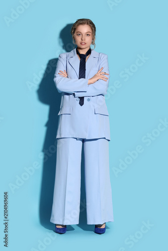 Beautiful young woman in stylish formal suit on blue background
