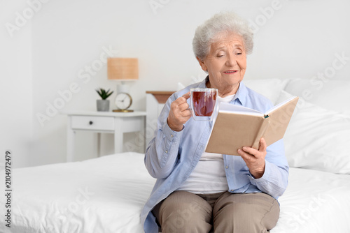 Senior woman with glass cup...