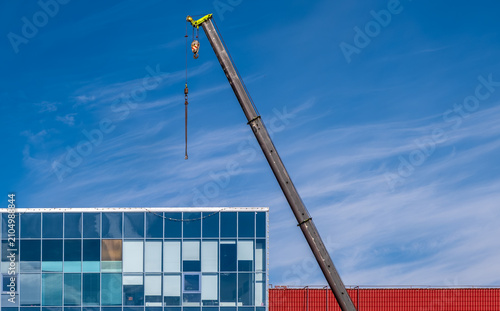 The retractable boom of the truck crane above the building.