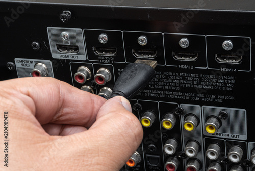 Close-up of hand connecting HDMI cable to home theater device