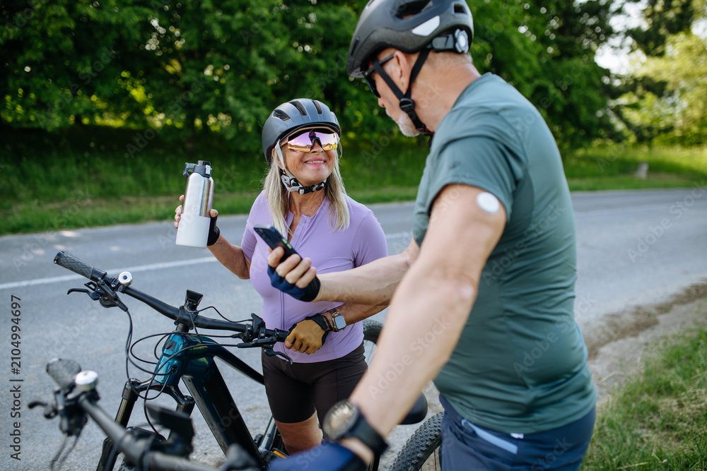 Obraz premium Active seniors with diabetes preparing for electric bike trip.