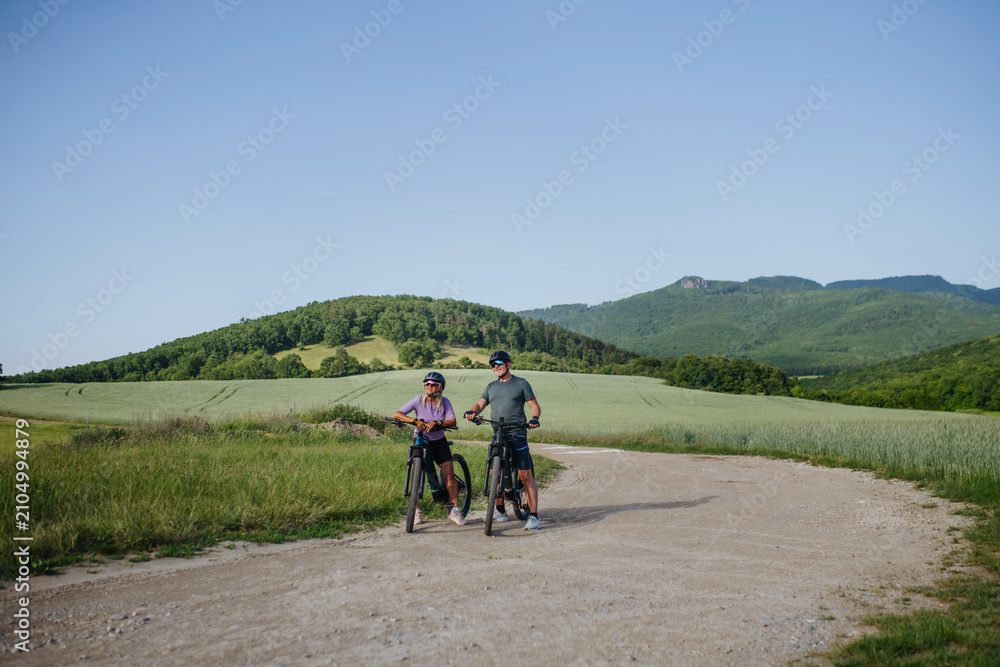 Obraz premium Active senior couple exploring nature on electric bicycles