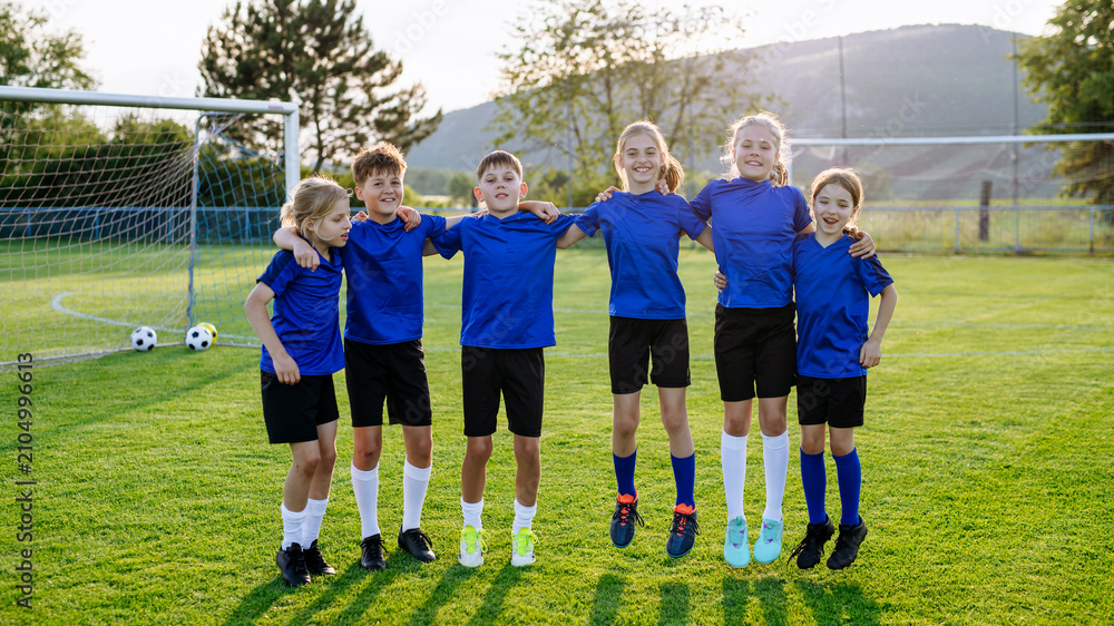 Fototapeta premium Mixed youth football team standing together on soccer field before training.