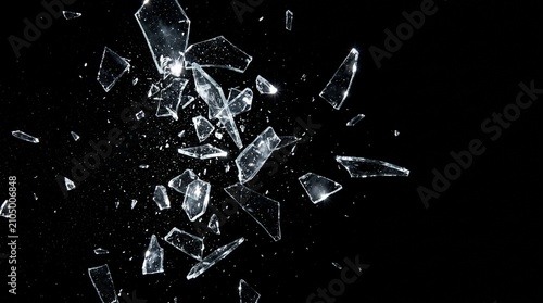 Sharp shards of broken glass exploding and flying through the air, isolated on a black background.