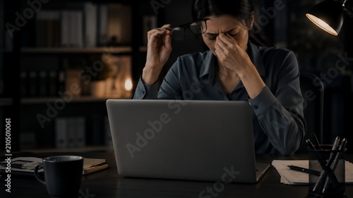 Stressed Businesswoman Rubbing Tired Eyes While Working Late on Laptop in Home Office, Digital Eye Strain and Work Burnout Concept