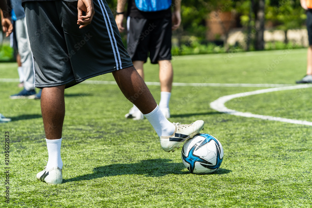 Fototapeta premium Close up feet of African male football player practicing with soccer ball. 
