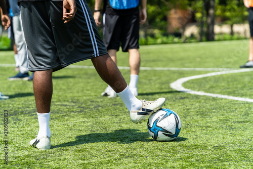 Close up feet of African male football player practicing with soccer ball. 