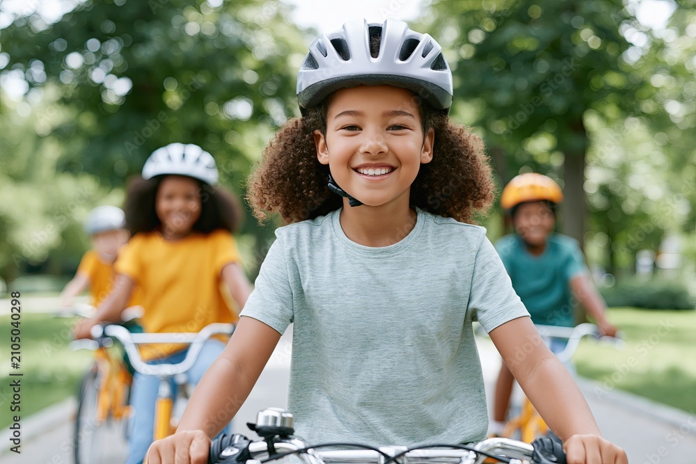 Fototapeta premium Smiling girl wearing helmet riding bicycle in park outdoor recreation