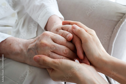 Young Caregiver Holding Senior Woman's Hands with Compassion at Home