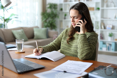 Tablou pe pânză Annoyed teleworker talking on phone and checking agenda
