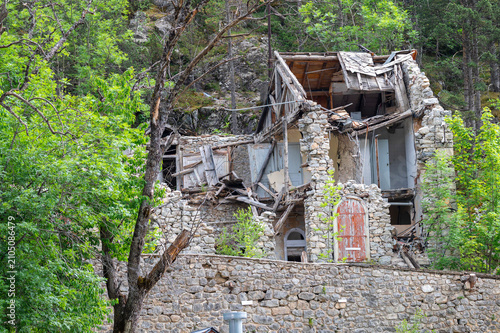 Canvastavla Old abandoned stone house in ruins with collapsed wooden roof structure on a wooded hillside, derelict rural building decaying in natural forest surroundings