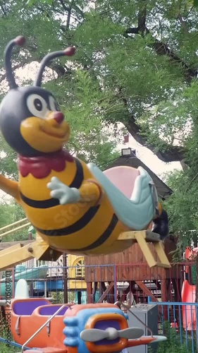 Young girl enjoying a fun carousel ride shaped like a bee at an outdoor amusement park