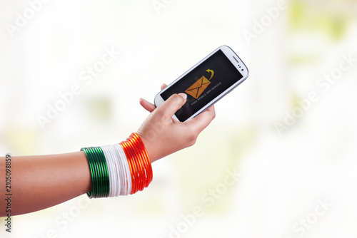 Foto WoMans hand with bangles in the colors of the national flag using mobile phone