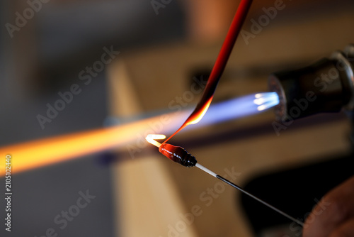Konstfotografi Extreme close-up of lampwork artist shaping molten glass bead with torch flame