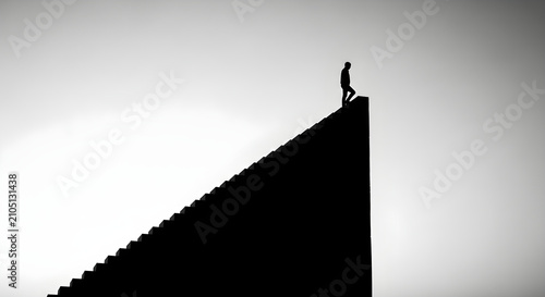 Silhouette of a lone person reaching the top of a steep staircase representing success and personal growth