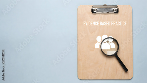 Evidence based practice concept with a wooden clipboard and magnifying glass