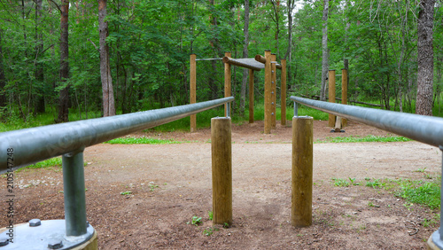 Quadro su tela Parallel bars and various wooden fitness stations creating an outdoor workout ar