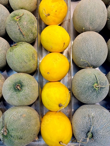 Obraz na plátně Symmetrical display of yellow honeydew melons flanked by green cantaloupe melons
