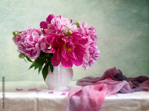 Still life with a bouquet of pink peonies in a white vase on a light background