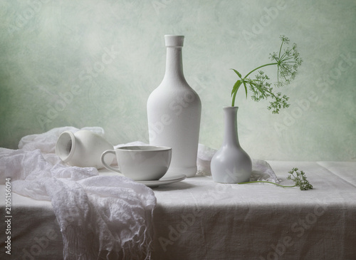 Contemporary still life with a flower and white dishes on a light background