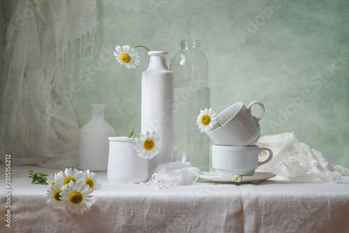 Photography Contemporary still life with daisies and white dishes on a light background