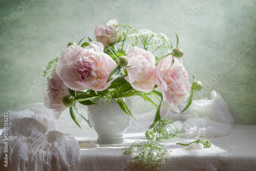 Still life with a bouquet of pink peonies in a white vase on a light background