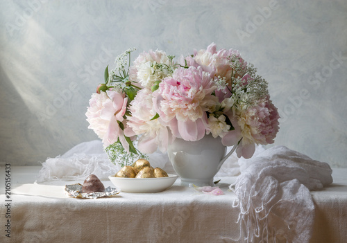 Still life with a bouquet of pink peonies in a white vase on a light background