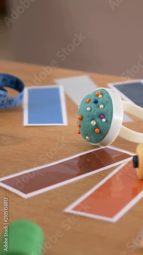 Vertical video: Panning camera drawing pincushion into focus at table for swatches with blue tape