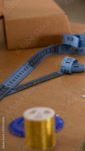 Vertical video: Panning camera moving across craft table, showing gold bobbin, measuring tape, box