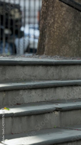 Vertical video: Entering frame person in beige trousers crossing stone steps with brown bag and cup