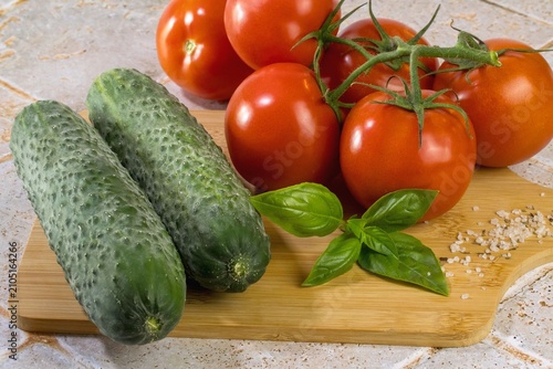 Concombres tomates basilic sur une planche en cuisine