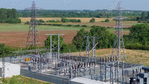 Detailed aerial view of small electrical substation and high voltage power line pylon in rural field