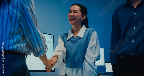 Close up multiracial group young Asia businesspeople in smart casual wear discussing business shaking hand together while stand in modern night office. Partner cooperation, coworker teamwork concept.
