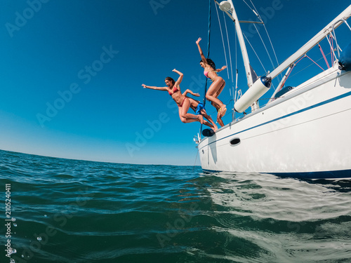 Happy friends diving from sailing boat into the sea - Travel and summer vacation concept - Soft focus on blond girl face - UGC wide lens content