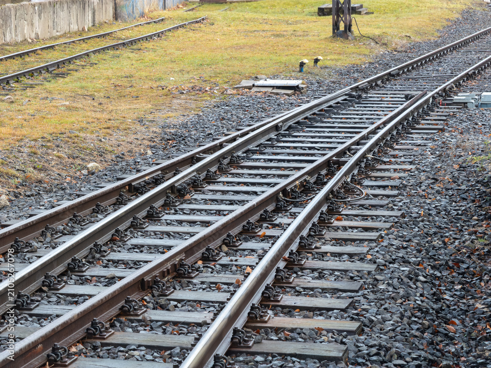 Obraz premium A pair of parallel metal railway tracks curves across a gravel bed, illustrating infrastructure and connectivity in a rural setting where steel rails guide public transportation travel
