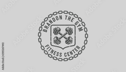 Gym fitness center vintage badge design featuring crossed dumbbells in a shield surrounded by a strong metal chain.