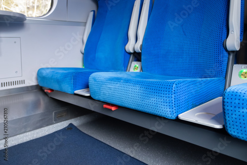 фотографія Empty blue upholstered train seats with white pull-out tables in a modern carria