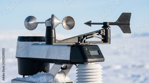Weather station anemometer measuring wind speed and direction in snowy arctic landscape, meteorology and climate monitoring concept