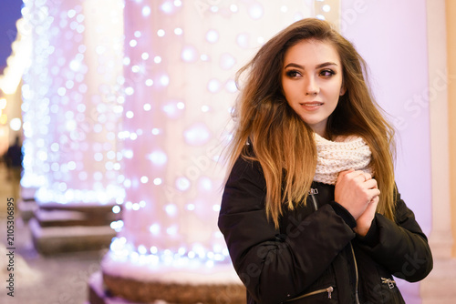 Fotografie Young Woman by Festive City Lights on a Winter Night