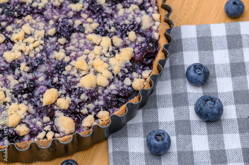Appetizing sweet shortcrust pastry with blueberries, baked tart with crumble topping