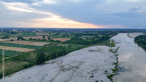 Po River experiencing extreme drought. Showing vast dry riverbed sections alongside the remaining water stream. Symbolizing environmental crisis