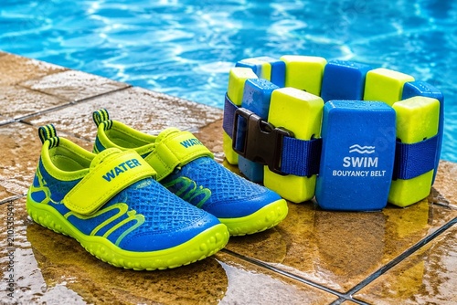 Fotografía A pair of bright training shoes and a buoyancy belt on wet poolside tiles