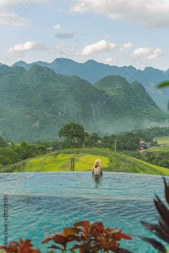 Fotografie Swimmer admiring golden rice terraces from infinity pool, Pu Luong, Vietnam